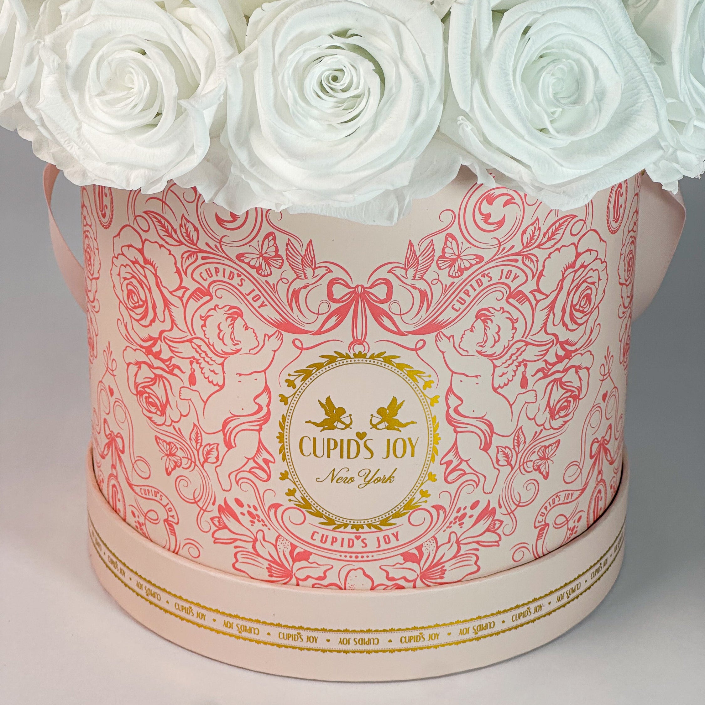 Cupid-motif box with white forever roses on a gray background